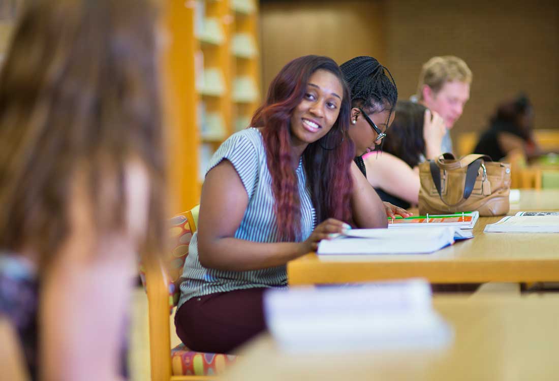 Students conversing and studying in the AUM library