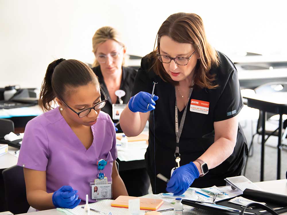 AUM Nursing instructure teaching a student how to suture